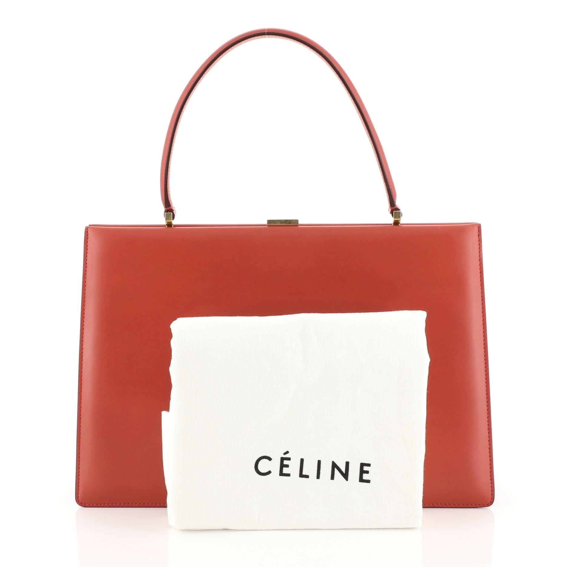 This Celine Clasp Top Handle Bag Leather Medium, crafted in red leather, features a leather top handle, stamped Celine logo, framed top, and gold-tone hardware. Its clasp closure opens to a black leather interior divided into two compartments with a