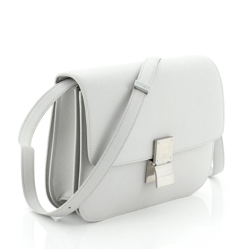 This Celine Classic Box Bag Grainy Leather Medium, crafted from gray grainy leather, features an adjustable strap and aged silver-tone hardware. Its push-tab closure opens to a gray leather interior with two open compartments, zip compartment and