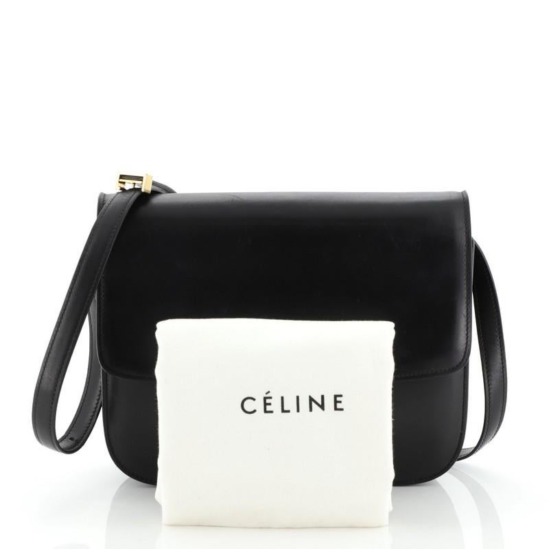 This Celine Classic Box Bag Smooth Leather Medium, crafted from black smooth leather, features a long adjustable strap and gold-tone hardware. Its push-tab closure opens to a black leather interior with two open compartments, zip compartment and