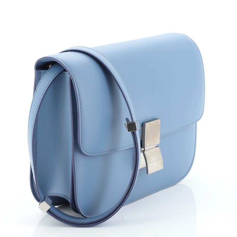 This Celine Classic Box Bag Smooth Leather Medium, crafted from blue smooth leather, features a long adjustable strap and gold-tone hardware. Its push-tab closure opens to a blue leather interior with two open compartments, zip compartment and slip