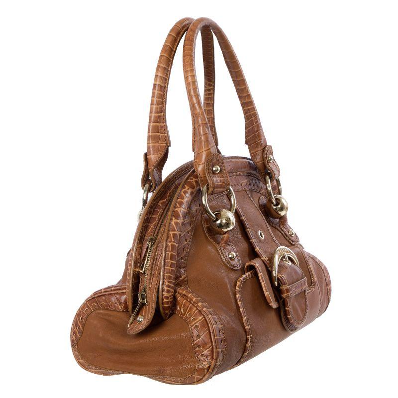 Celine doctors bag in cognac leather with faux crocodile details. Closes with a zipper on top. Lined in off-white monogram fabric with two open pockets against the front and a zipper pocket against the back. Has been carried with a few marks to the