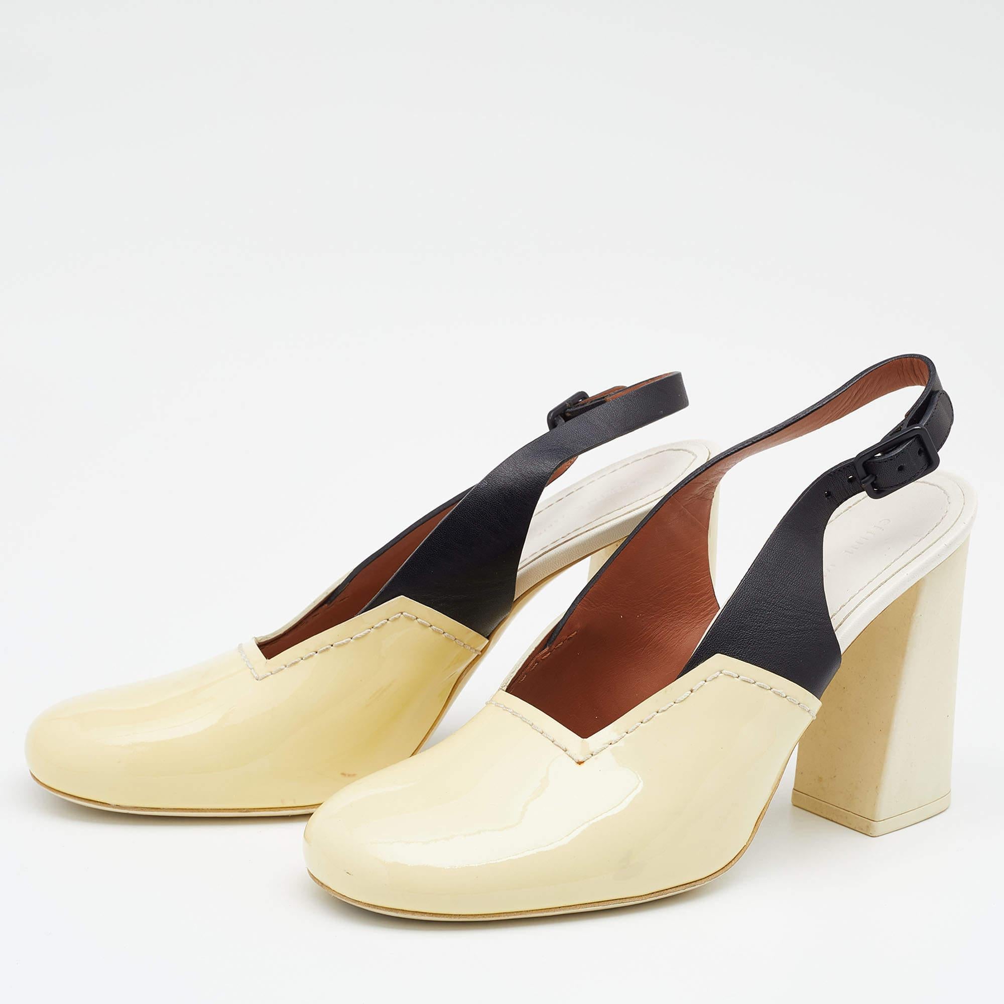 Walk stylishly as you flaunt these sandals from the House of Celine. Designed using cream black patent leather and leather these sandals are augmented with covered toes a buckled slingback and 10 cm block heels. They feature black toned hardware.