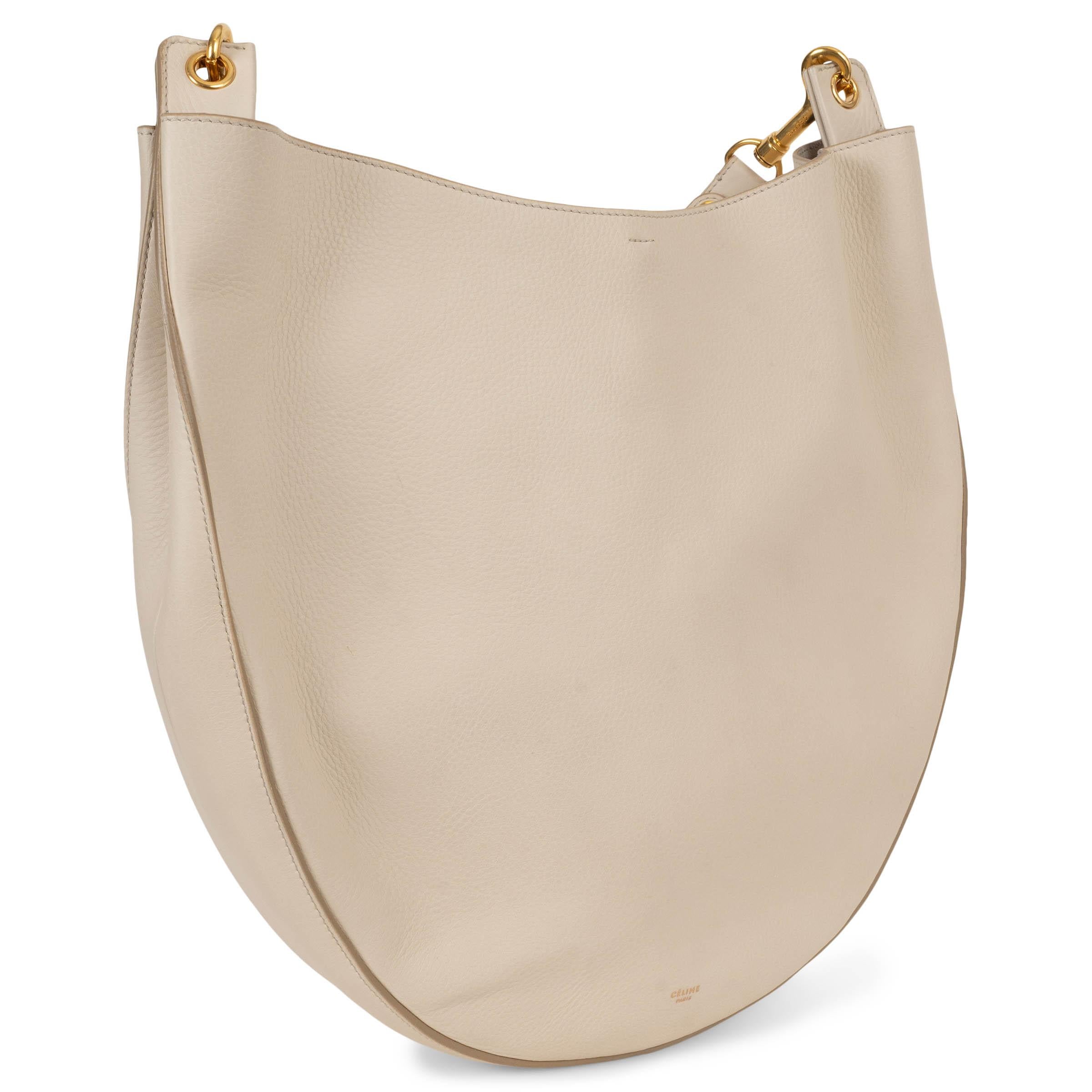 Ce sac à bandoulière 'Hobo Large' par Pheobe Philo en cuir de veau croustillant crème, 100% authentique, incarne le luxe tranquille avec sa forme sculpturale et son design minimaliste. La silhouette doucement structurée est dotée d'une bandoulière