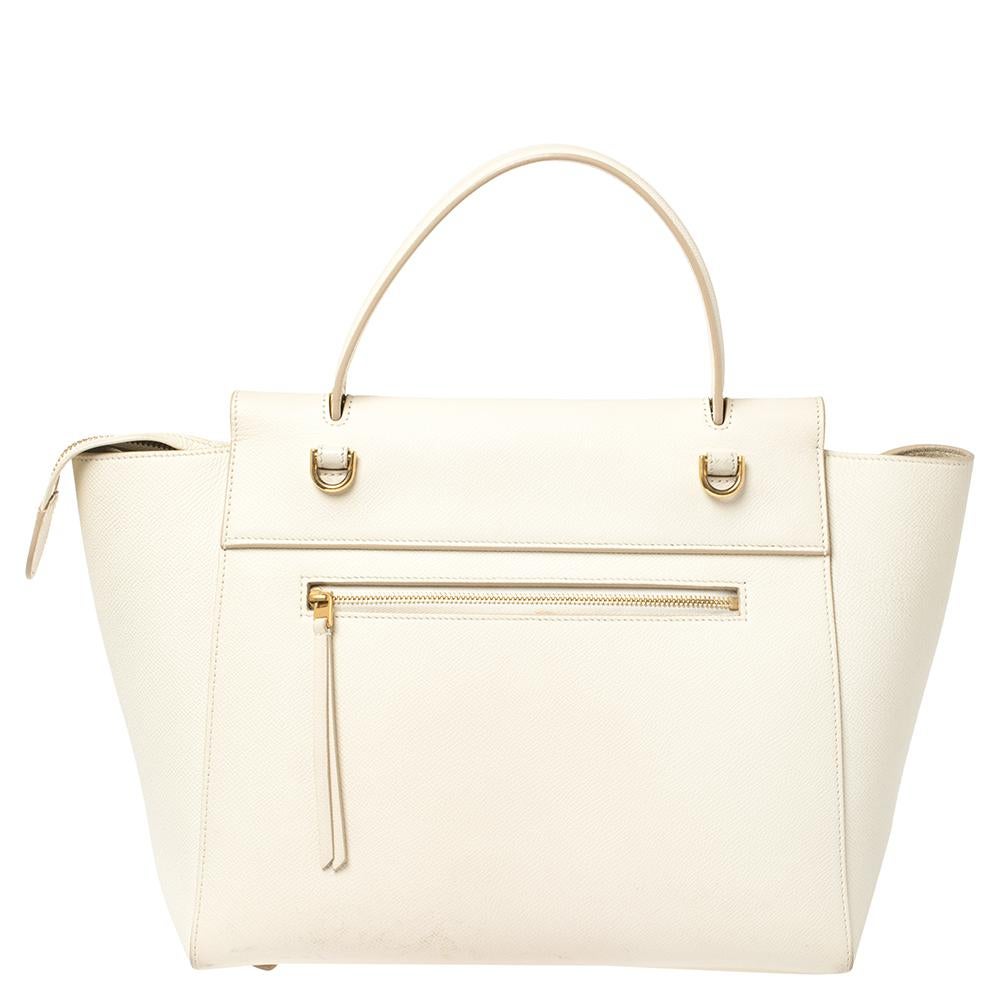 Taschen von Celine sind ein Symbol für exzellente Handwerkskunst und zeitloses Design. Diese cremefarbene Kreation wurde aus Leder gefertigt und mit einer Umschlagklappe und Gürteldetails versehen. Sie verfügt über einen einzelnen Griff an der