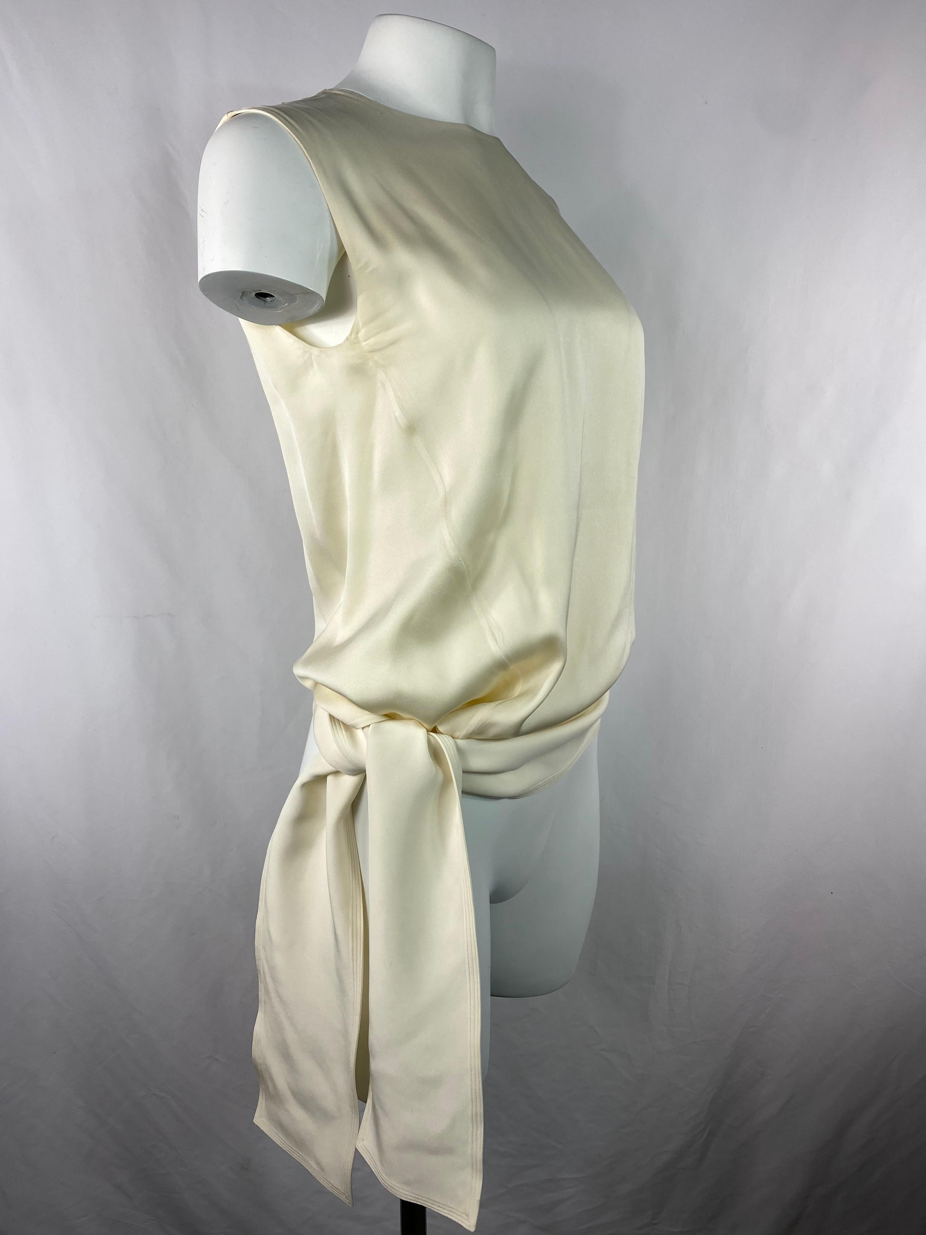 Product details:

The top made of 100% silk in cream/ ivory color, sleeveless  with crew neck line and size tie detail designed by Celine in Paris. It closures with rear zip and hook. 