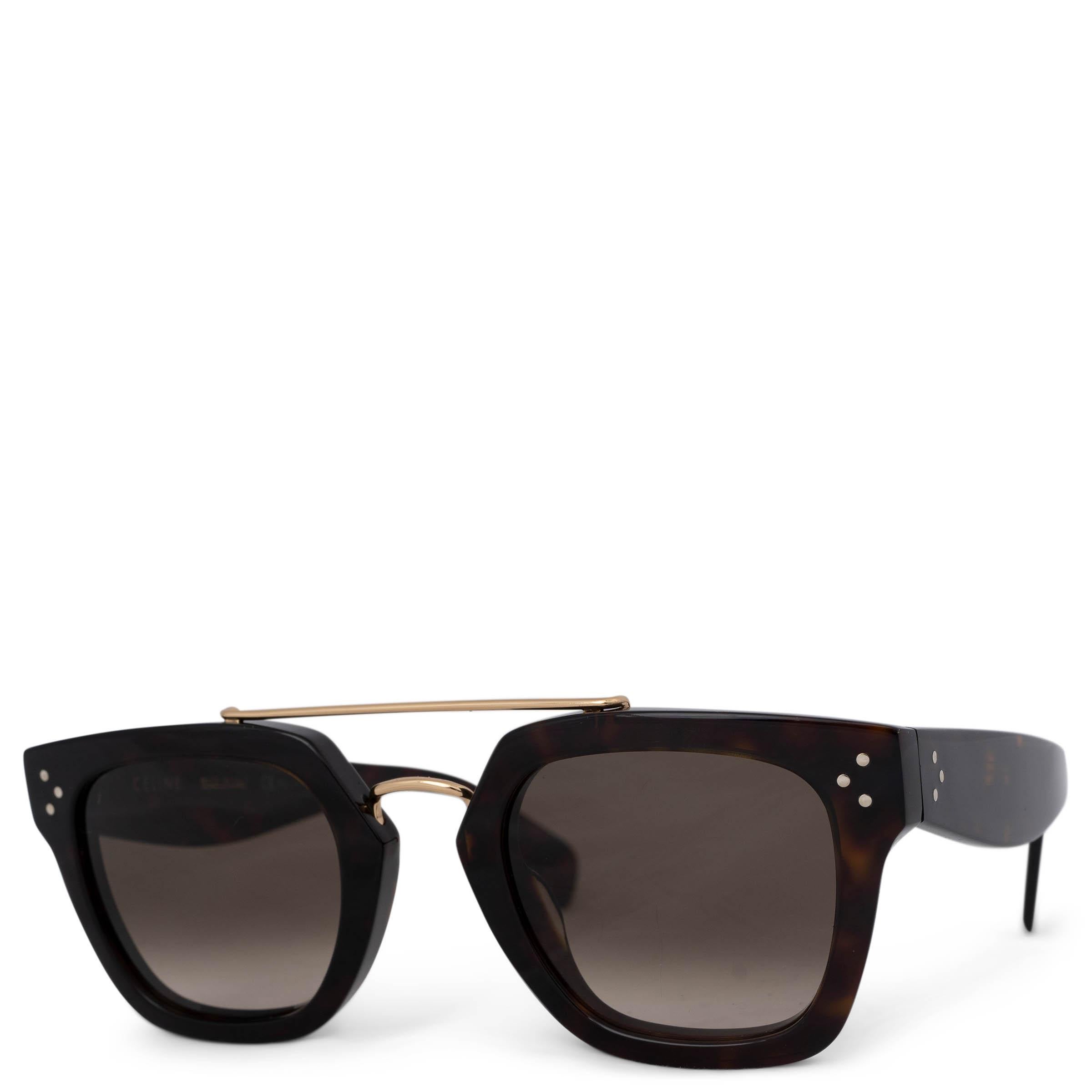 These 100% authentic Céline Bridge sunglasses are crafted from dark brown and amber acetate, featuring a sleek gold-tone metal bridge. The design is completed with stylish brown gradient lenses, offering both sophistication and UV protection.