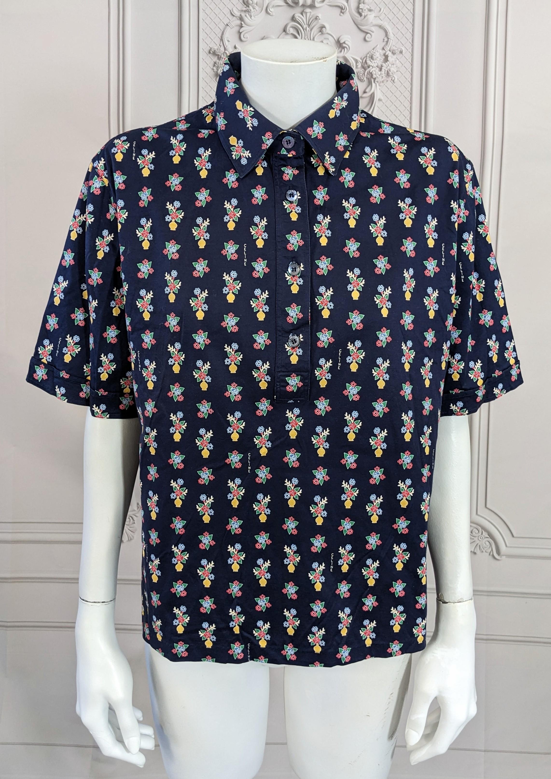 Celine cotton short sleeved polo of deep navy blue cotton lisle overall printed with floral bouquets and flower vases, in yellow, red, blues and greens. Logo signed Celine inside the print with mother of pearl Celine buttons. Very Good Condition.
