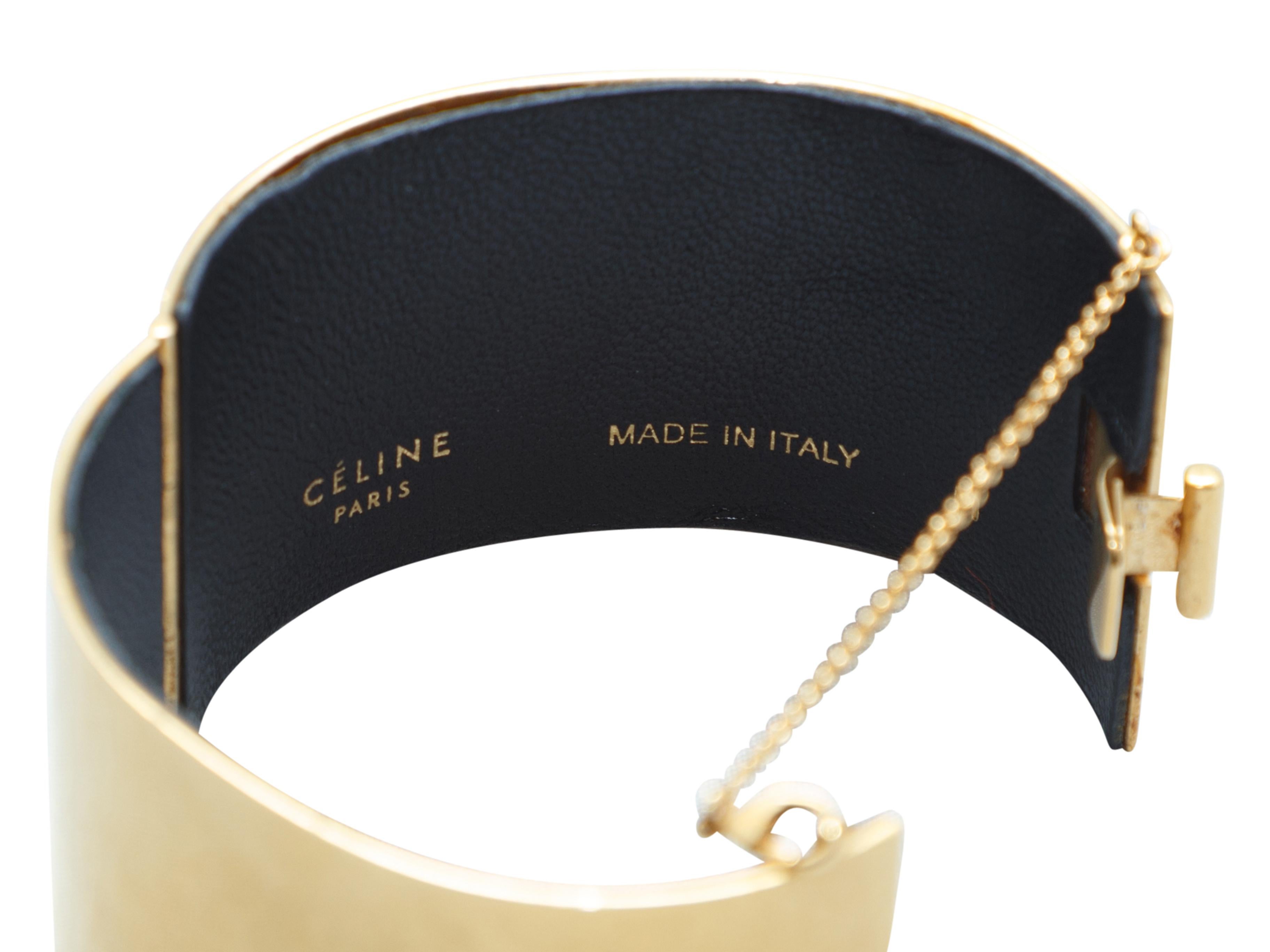 Product details: Gold-tone Edge cuff bracelet by Celine. Black leather at interior. Clasp closure featuring safety chain. 2