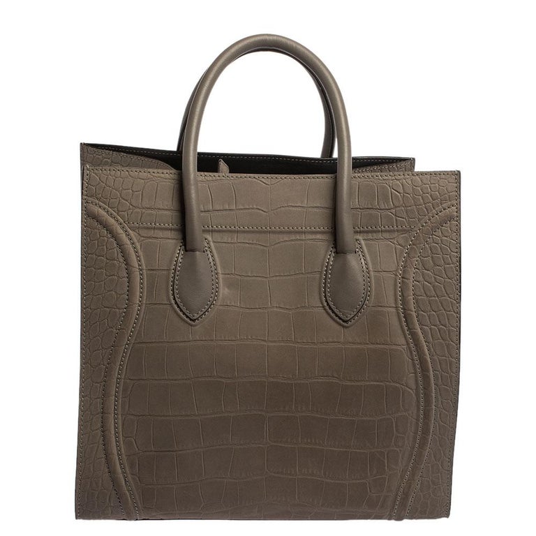 Celine released the Phantom as a newer version of its successful Luggage model. Unlike the Luggage toes, the Phantom has an open top, wider wingspans, and a braided zipper pull. We have here the one in croc-embossed leather. It has two top handles,