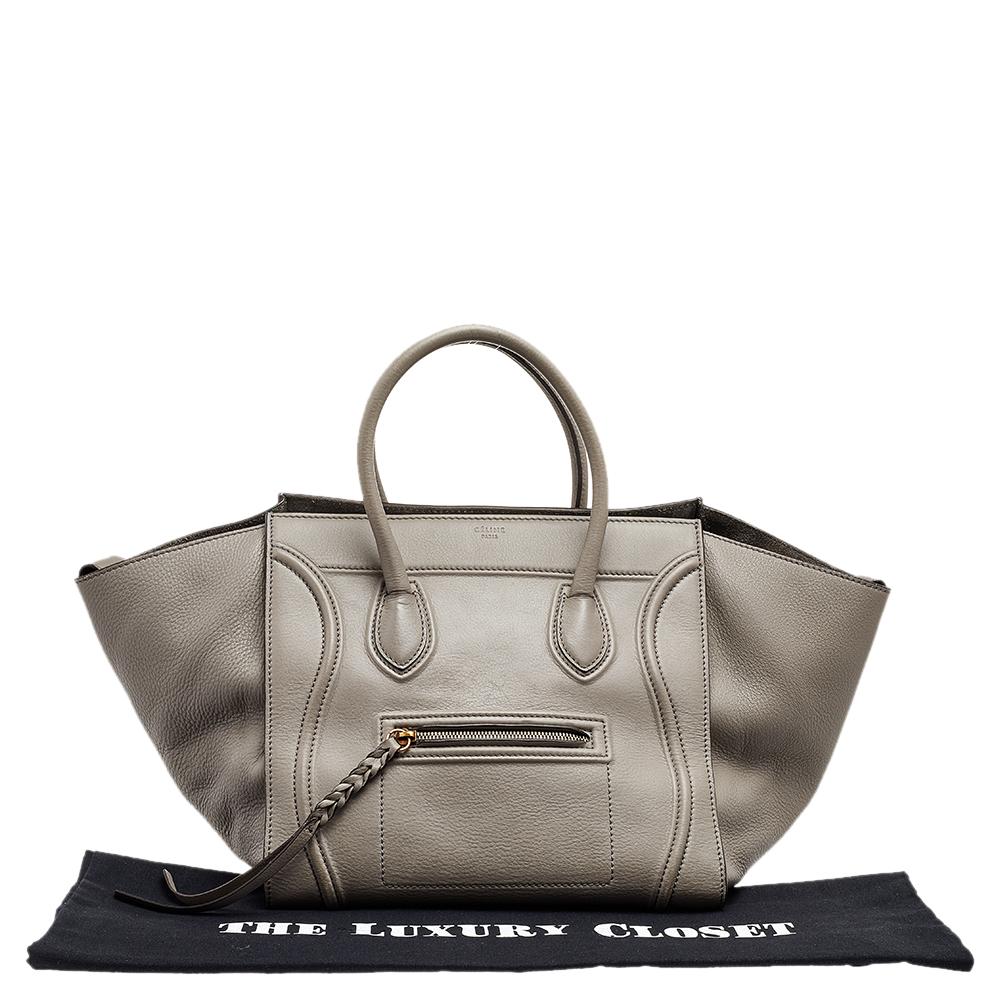 Celine released the Phantom as a newer version of their successful Luggage model. Unlike the Luggage toes, the Phantom has an open-top, wider wingspans, and a braided zipper pull. We have here the one in leather. It has two top handles, a grey