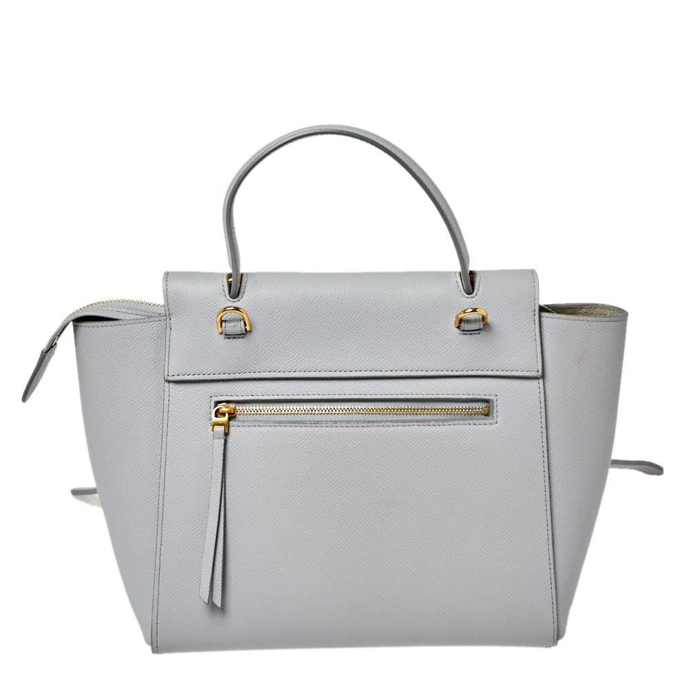 This Celine flap bag is a timeless creation that will never go out of style. Crafted from leather, it comes in a lovely shade of grey. It is equipped with a top handle, a front flap that opens to reveal a spacious suede interior with enough space to