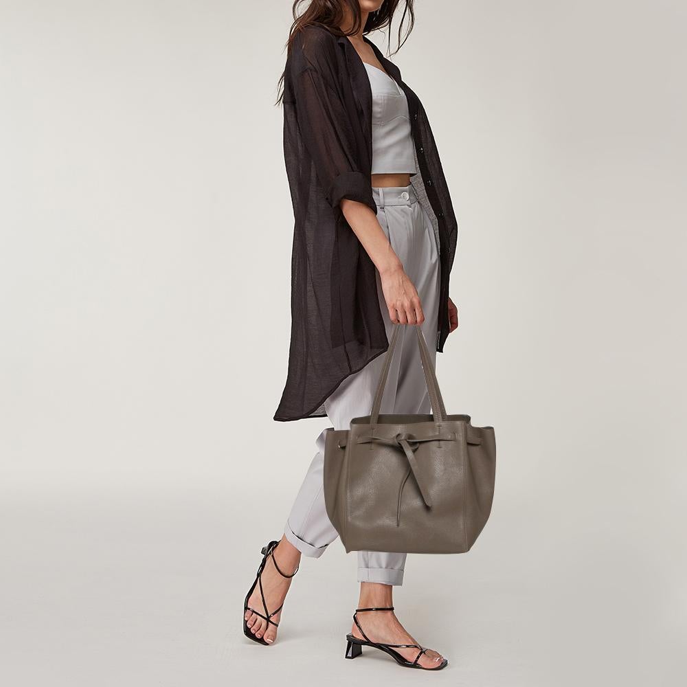 You can surely count on this astonishing Cabas Phantom tote by Celine. Crafted from leather, it features dual top flat straps and counters a suede-lined interior. This minimalist grey-hued tote comes with a zipper and a slip pocket on the interior