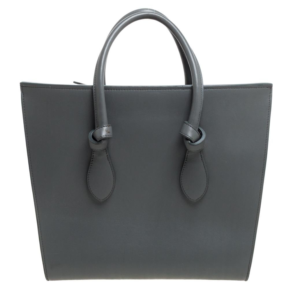 This Tie tote from Celine brings a wonderful mix of fashion and function. Expertly crafted from leather, it comes in a lovely shade of grey with dual top handles and metal studs to protect the base. Made in Italy, it has a spacious interior lined