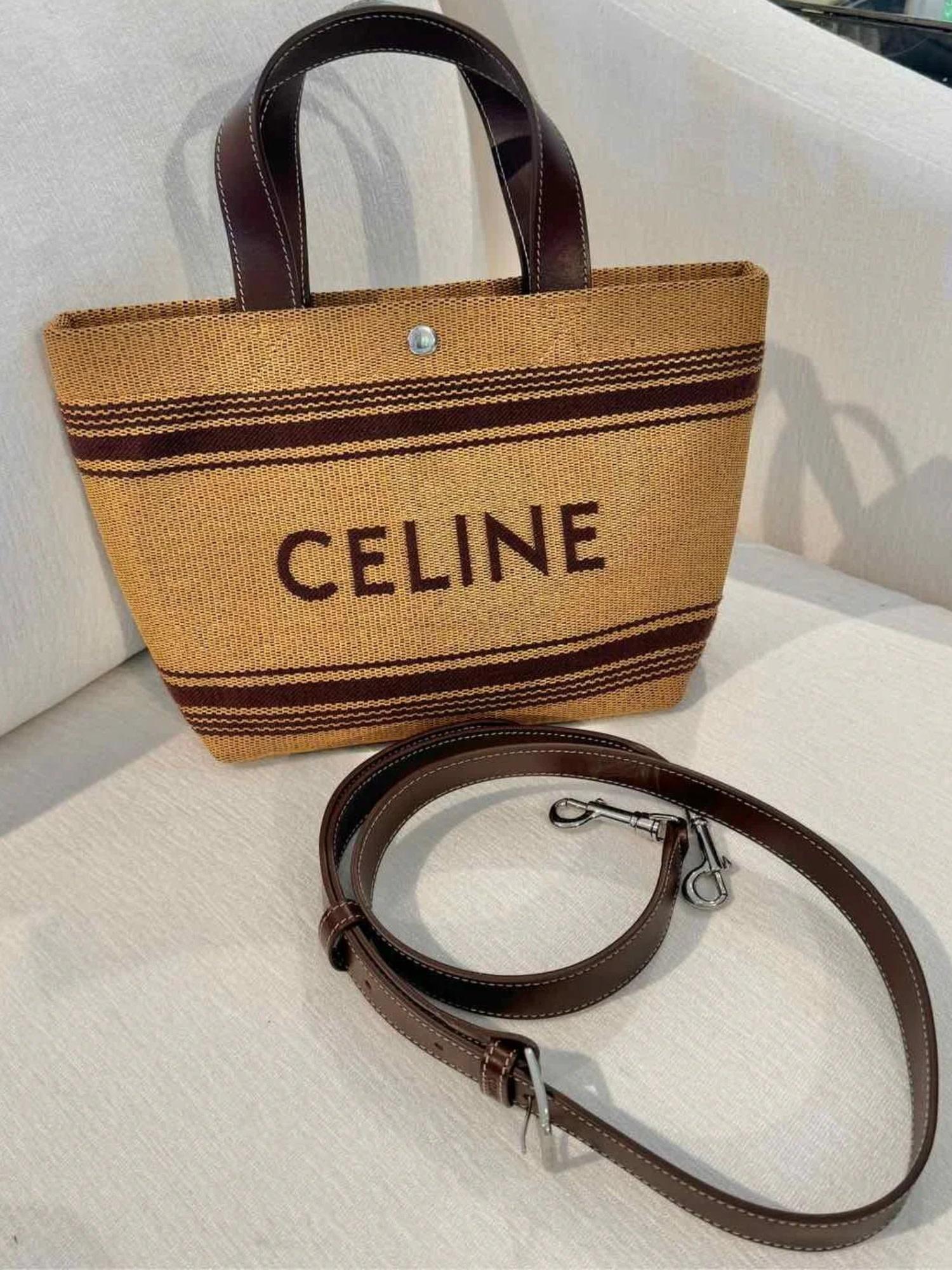 This mini cabas tote bag is constructed of raffia with brown leather details. It features an embroidered logo on the front, patterned stripes along the top and bottom, dual leather top handles, and silver-tone hardware. The open top is secured with