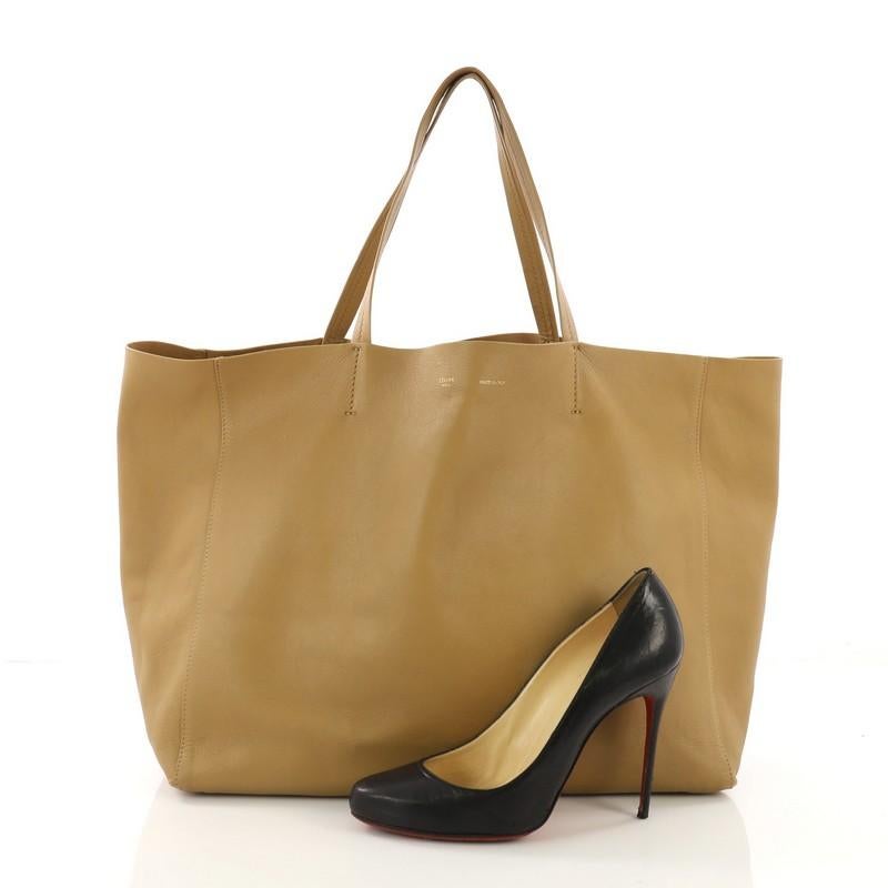 This Celine Horizontal Cabas Tote Leather Large, crafted in tan leather, features dual flat leather handles, stamped Celine logo at the center, and gold-tone hardware. Its wide open top showcases a tan microfiber interior with zip pocket. **Note: