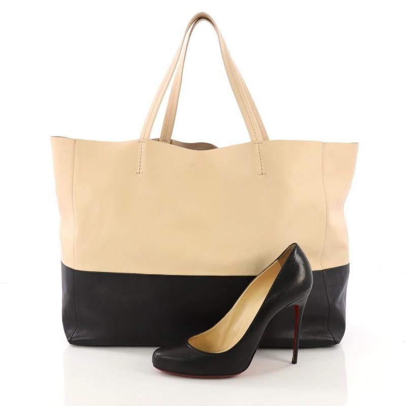 This Celine Horizontal Bi-Cabas Tote Leather Large, crafted in beige and black leather, features dual flat leather handles, stamped Celine logo at the center, and gold-tone hardware. Its wide open top showcases a beige and black suede interior with