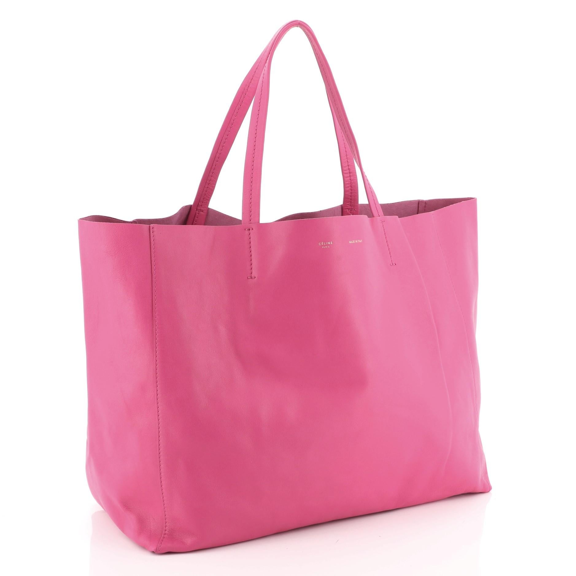This Celine Horizontal Cabas Tote Leather Large, crafted in pink leather, features dual flat leather handles, stamped Celine logo at the center, and aged gold-tone hardware. Its wide open top showcases a pink raw leather interior with zip pocket.