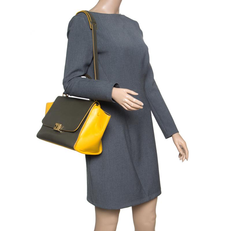 A staple in every fashionista's closet, this Trapeze bag from Celine is a breathtaking piece that will leave your audience gasping. Flaunting signature flappy wings and a leather exterior carrying khaki and yellow hues, the bag comes with a flap
