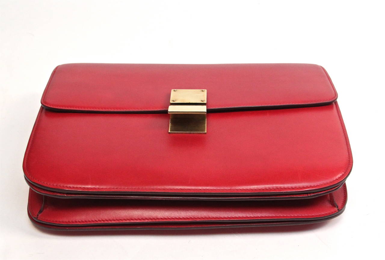 Supple, smooth red leather bag with antiqued brass-tone hardware designed by Phoebe Philo for Celine Spring 2012. Bag has a fold-over front flap with push lock closure. Bag measures approximately 11.5'' at widest x 9'' tall at center x 3'' deep and
