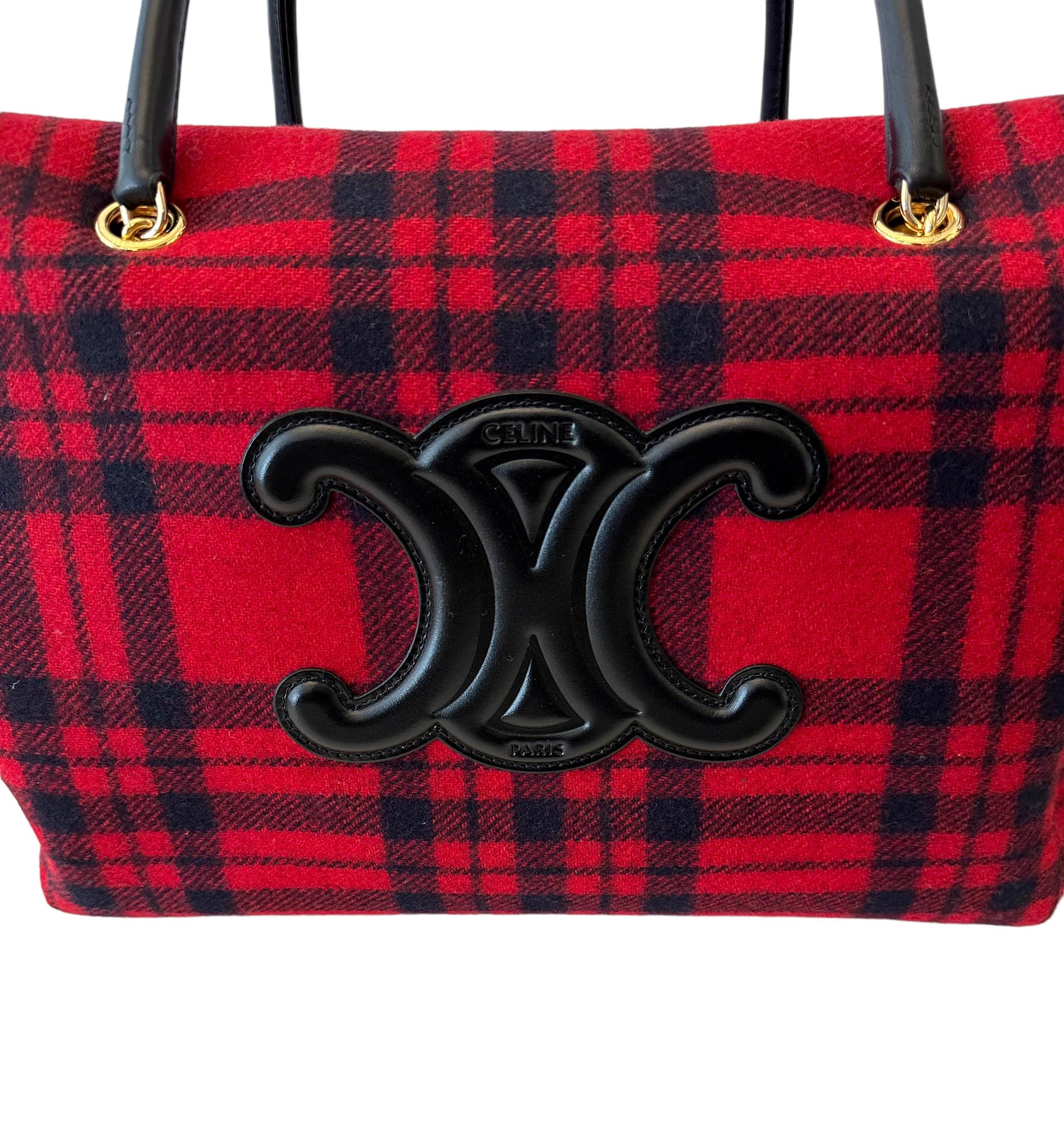 Créé par Hedi Slimane pour Céline en 2021, ce sac fourre-tout est confectionné dans un tissu écossais en laine noire et rouge.
Il présente un logo surdimensionné en cuir de veau noir ainsi que des poignées en cuir de veau noir et une fermeture à