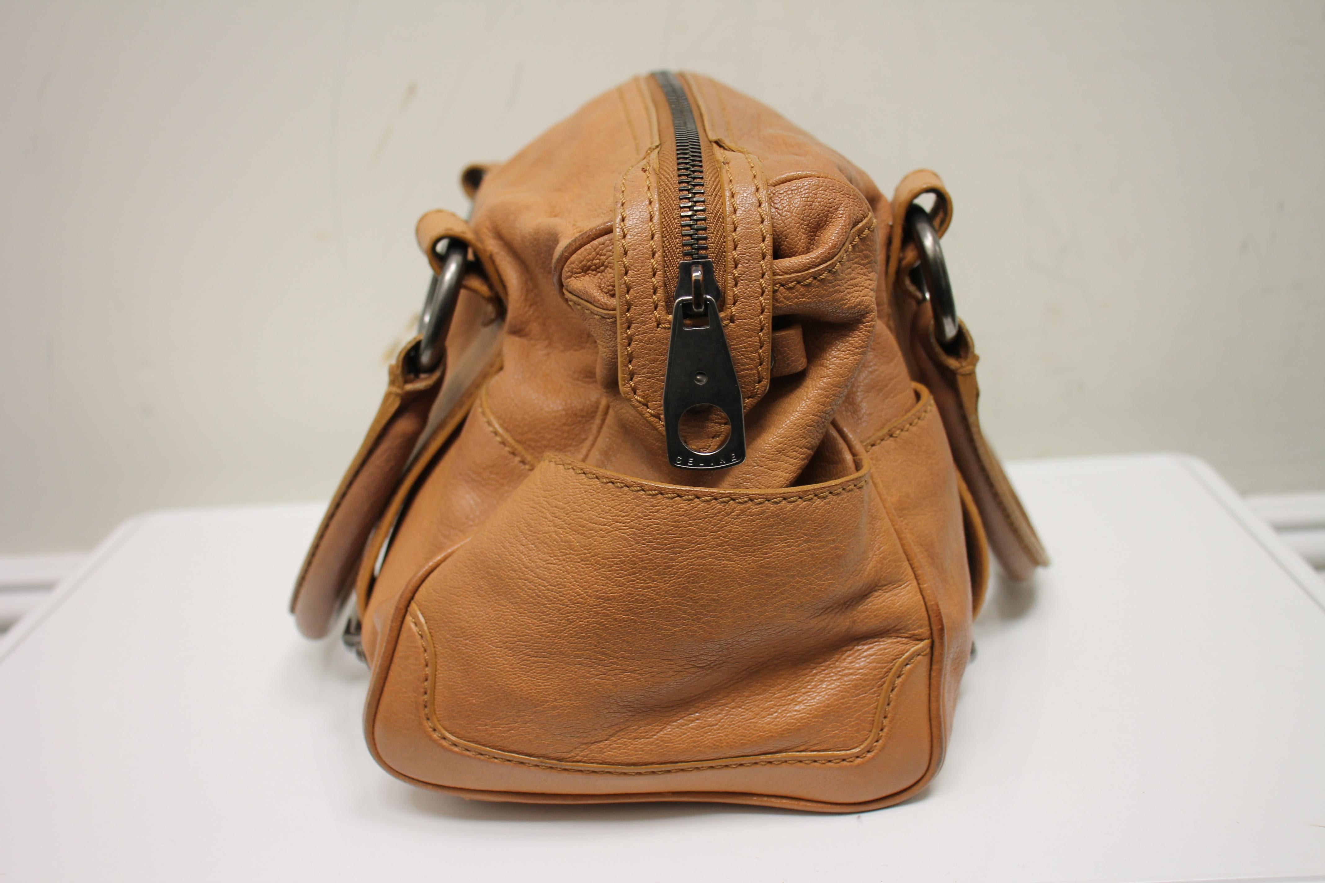 Brown grained leather. Antiqued silver-tone hardware. Zipper closure at top. Dual rolled top handles. Side exterior pockets. One exterior pocket with front flap closure. Lined interior. One interior zippered pocket.