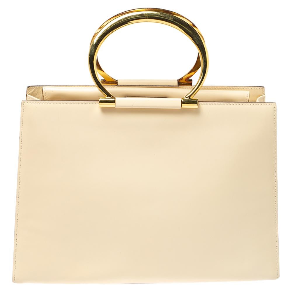 Swing this light cream-hued beauty in style. The creation is from Celine, made from leather in a structured silhouette and equipped with a sizeable fabric interior. The tote features two metal ring handles and metal studs to protect the base.

