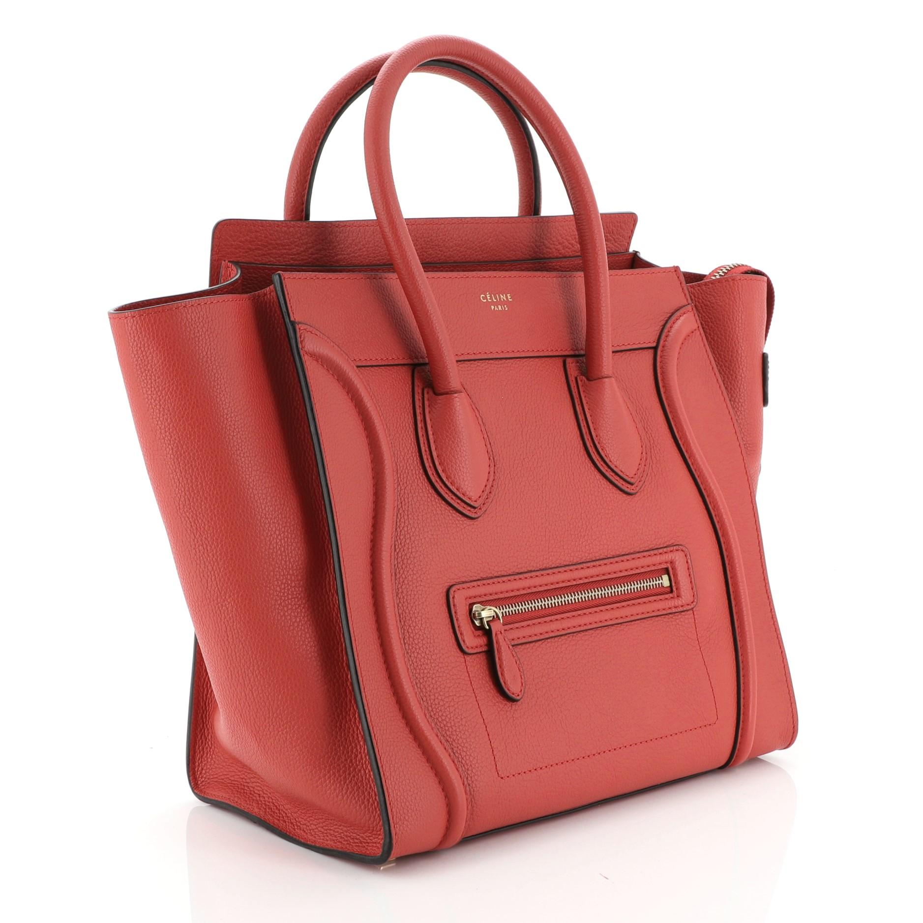 This Celine Luggage Bag Grainy Leather Mini, crafted from red grainy leather, features dual rolled handles, exterior front zip pocket, and aged gold-tone hardware. Its zip closure opens to a red microfiber interior with side zip and slip pockets.