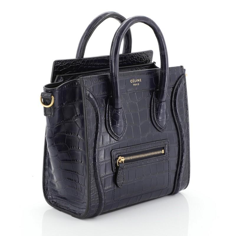 This Celine Luggage Handbag Crocodile Nano, crafted in genuine blue crocodile skin, features dual rolled handles, front zip pocket, and aged gold-tone hardware. Its zip closure opens to a blue leather interior with side slip pocket.  This item can