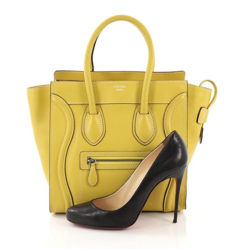 This Celine Luggage Handbag Grainy Leather Micro, crafted in yellow grainy leather, features dual rolled leather handles, exterior zip pocket, and silver-tone hardware. Its zip closure opens to a yellow suede interior with zip and slip pockets.