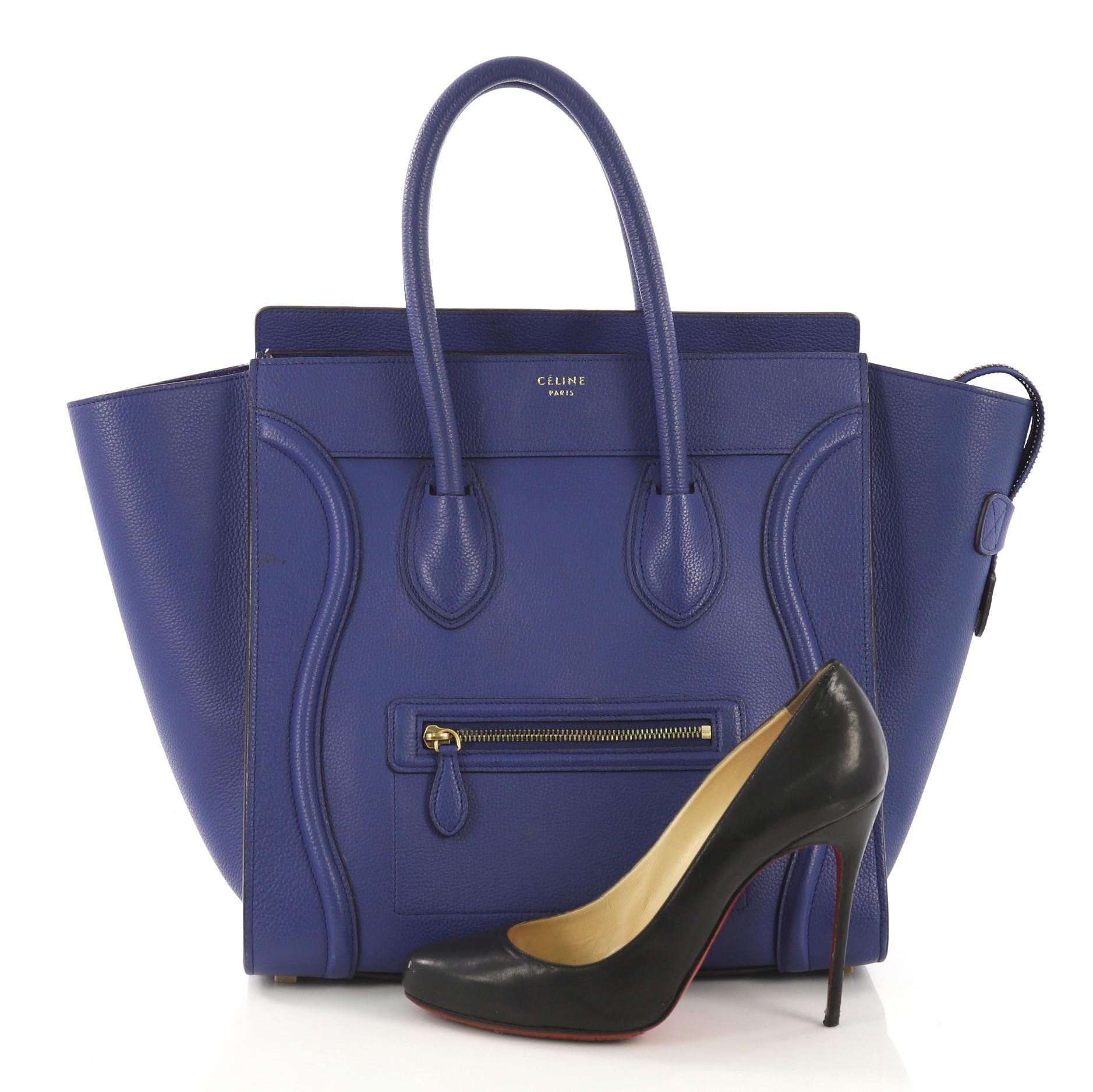 This Celine Luggage Handbag Grainy Leather Mini, crafted in blue grainy leather, features dual rolled leather handles, front zip pocket, and aged gold-tone hardware. Its zip closure opens to a blue suede interior with zip and slip pockets. **Note: