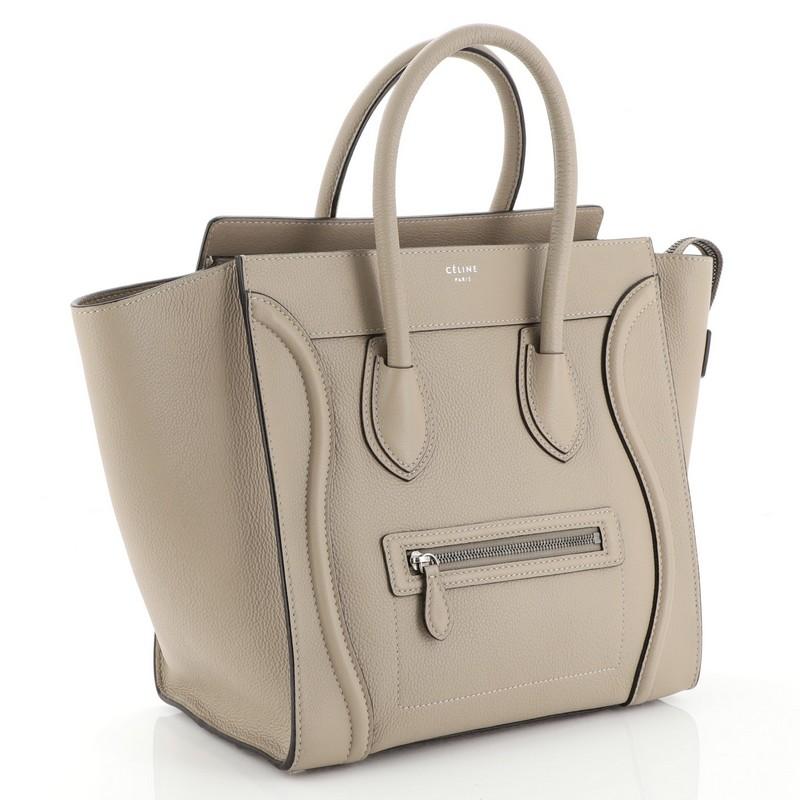 This Celine Luggage Handbag Grainy Leather Mini, crafted from neutral grainy leather, features dual rolled handles, exterior front zip pocket, and aged silver-tone hardware. Its zip closure opens to a neutral suede interior with side zip and slip