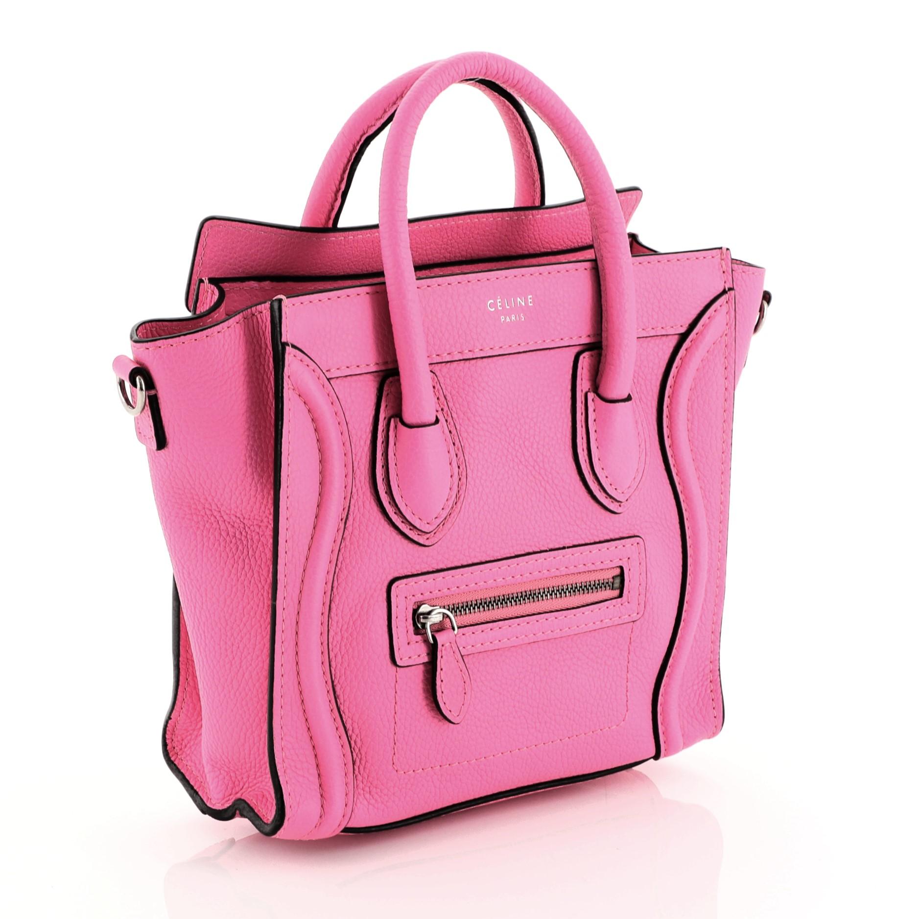 This Celine Luggage Handbag Grainy Leather Nano, crafted in pink grainy leather, features dual rolled leather handles, front zip pocket, and silver-tone hardware. Its zip closure opens to a pink microfiber interior with zip and slip