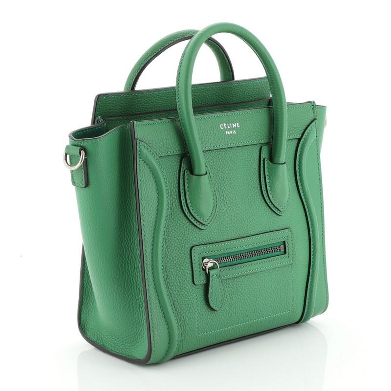 This Celine Luggage Handbag Grainy Leather Nano, crafted in green grainy leather, features dual rolled leather handles, front zip pocket, and aged silver-tone hardware. Its zip closure opens to a green suede interior with zip and slip pockets.