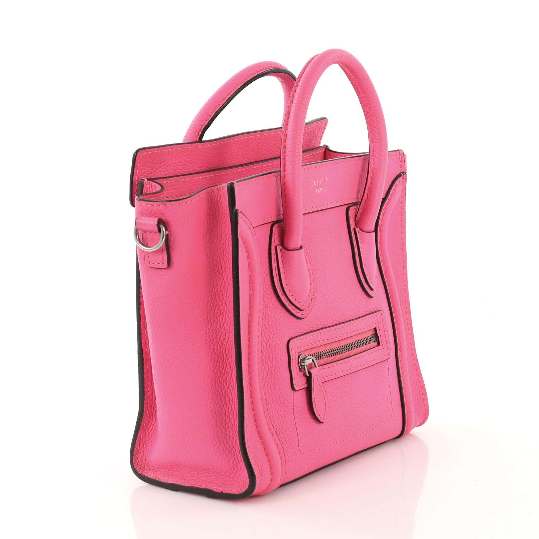 This Celine Luggage Handbag Grainy Leather Nano, crafted in hot pink grainy leather, features dual rolled leather handles, front zip pocket, and silver-tone hardware. Its zip closure opens to a pink microfiber interior with zip and slip pockets.