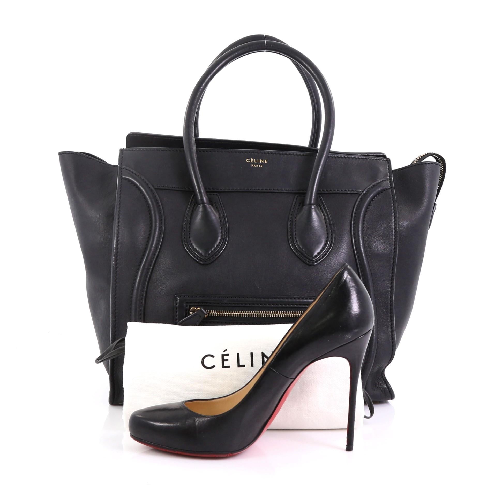 This Celine Luggage Handbag Smooth Leather Mini, crafted in black smooth leather, features dual rolled leather handles, front zip pocket, leather trim, protective base studs, and aged gold-tone hardware. Its top zip closure opens to a black leather