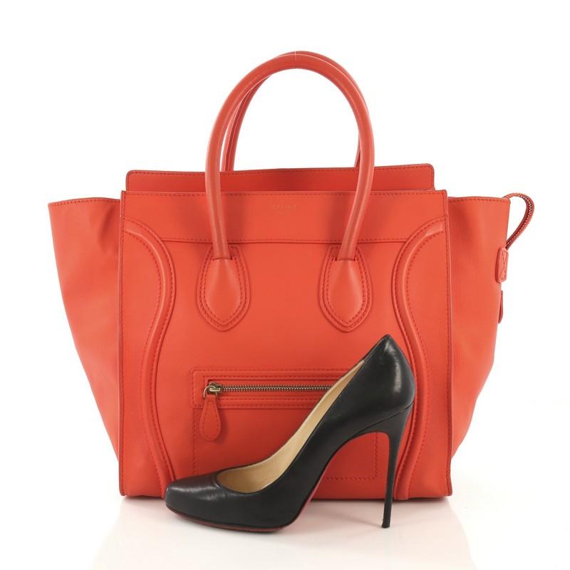 This Celine Luggage Handbag Smooth Leather Mini, crafted in orange smooth leather, features dual rolled leather handles, front zip pocket, protective base studs, and aged gold-tone hardware. Its top zip closure opens to an orange leather interior