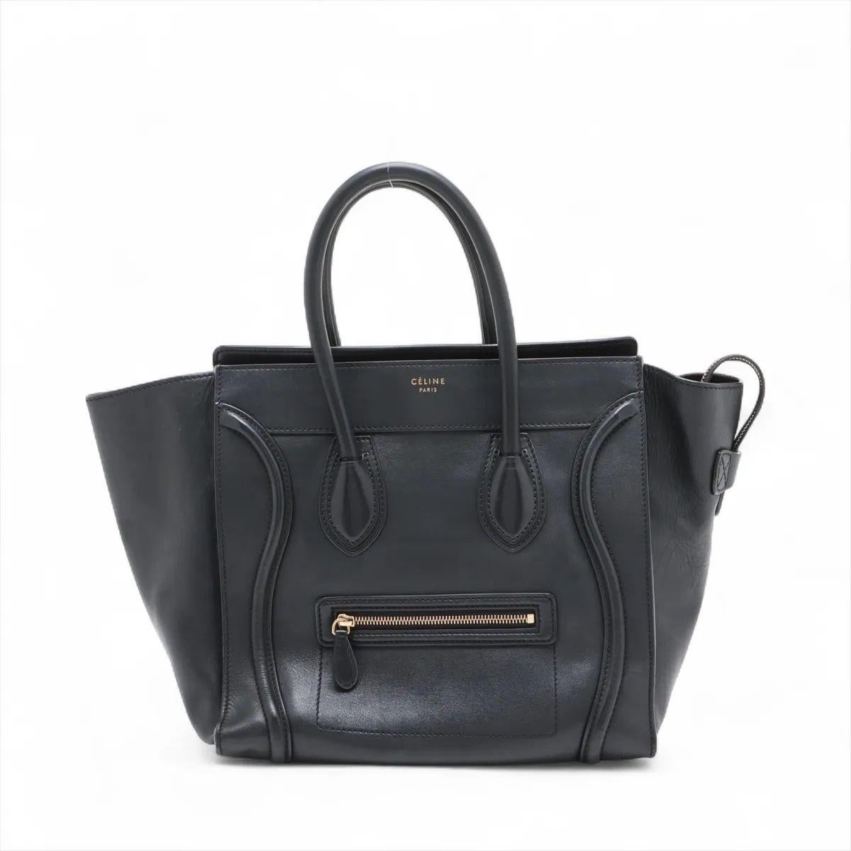 The Celine Luggage Mini Shopper Leather Handbag in black is an iconic piece that blends bold design with timeless elegance. Crafted from smooth, high-quality leather, it showcases the brand’s signature structured silhouette with its distinctive
