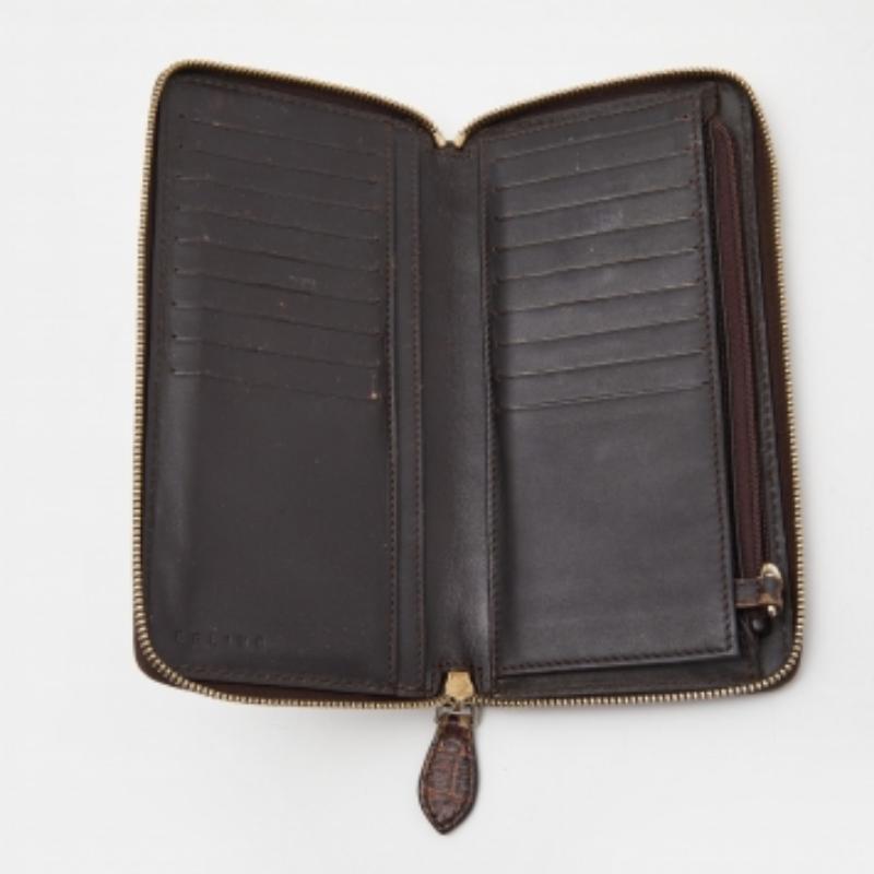 Esta cartera de Celine es un accesorio realmente chic y elegante. Está confeccionada con lona marrón Macadam y piel con relieve de cocodrilo en el exterior, con herrajes dorados que realzan su aspecto. Tiene el interior forrado de piel y tela.