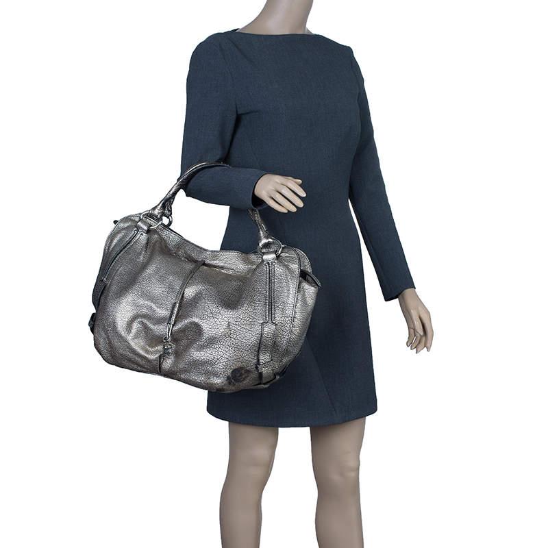 This spacious Celine ‘Bittersweet’ hobo is stylish and practical. It is crafted from silver metallic leather and is equipped with leather trim handles a top zip closure and a hidden drawstring with a charm at the front. The spacious bag opens up to