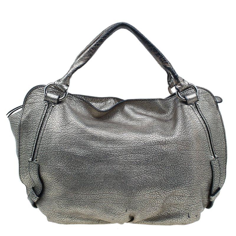 This spacious Celine ‘Bittersweet’ hobo is stylish and practical. It is crafted from silver metallic leather and is equipped with leather trim, handles, a top zip closure and a hidden drawstring with a charm at the front. The spacious bag opens up