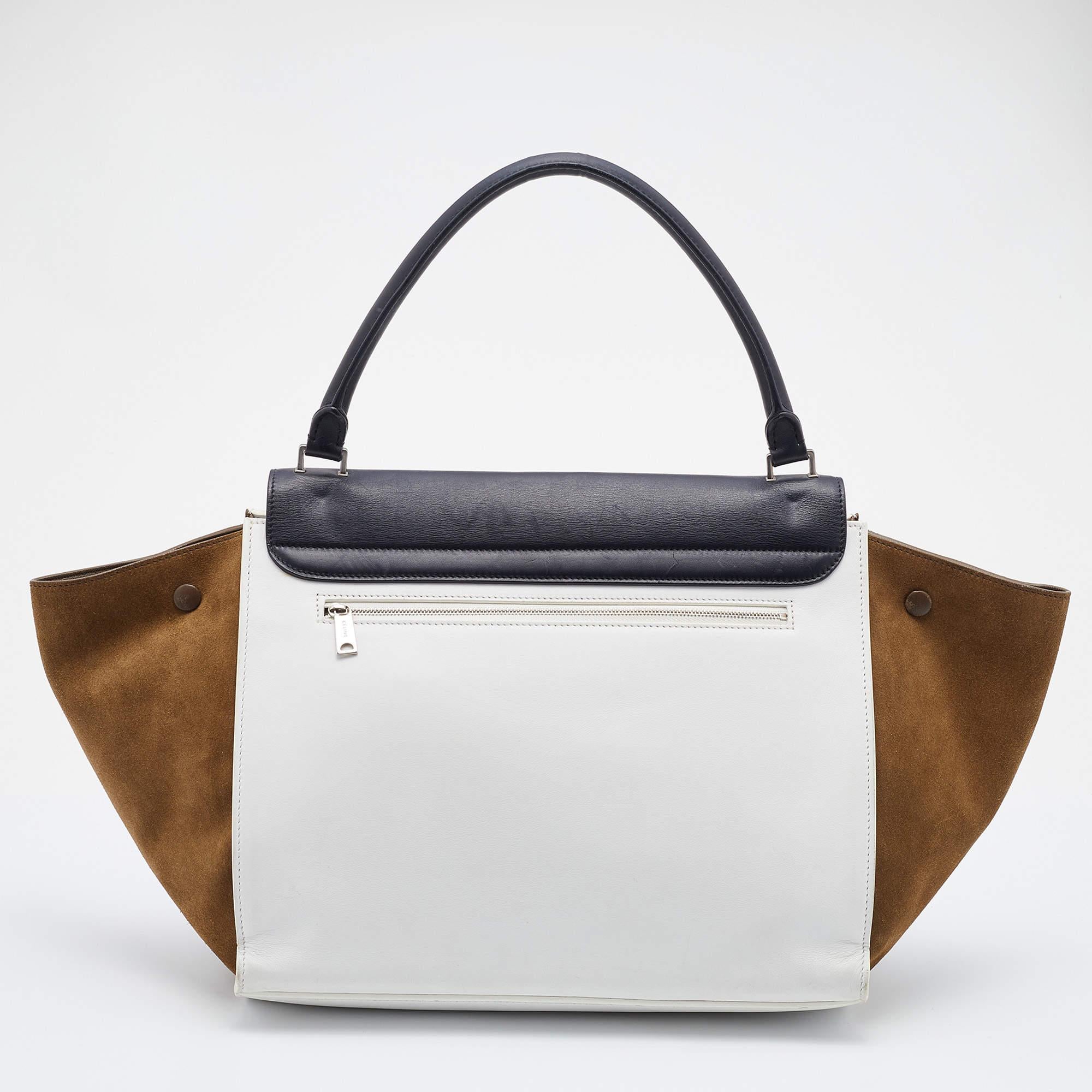 This Trapeze bag from the House of Celine is crafted beautifully to perfection. It is made from tricolored leather and suede into a sturdy silhouette and enhanced with silver-tone hardware. It has a top handle and a spacious leather-lined interior.

