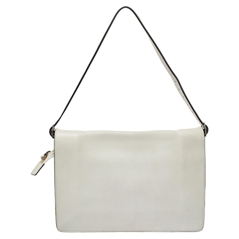 This stylish and effortless shoulder bag hails from the house of Celine. It has been crafted from quality leather and comes in an off-white shade. It has been designed with a single strap, a front flap with a clasp that opens to reveal a