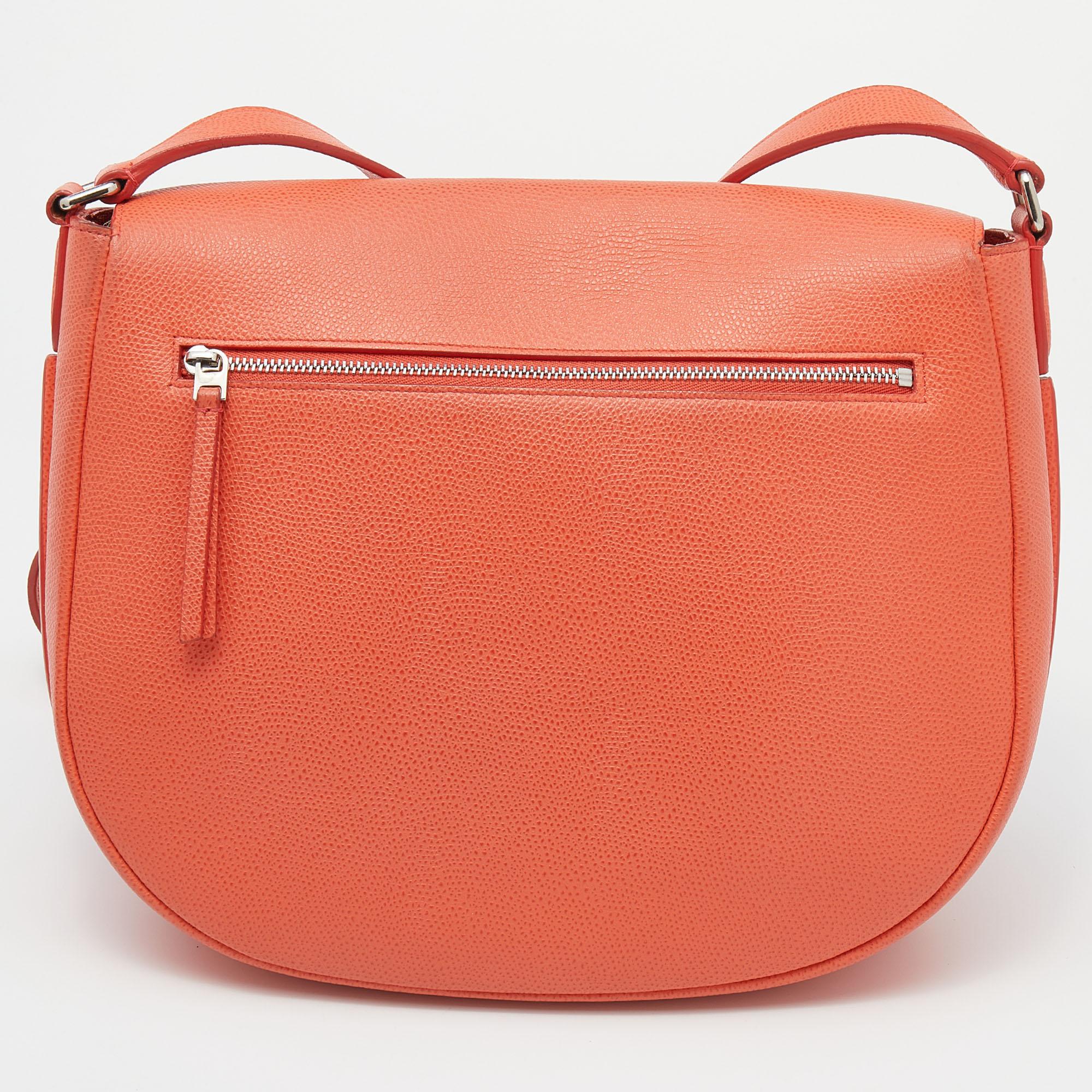 How gorgeous and adorable is this Trotteur messenger bag from Celine! It is made from orange leather on the exterior. Its sturdy shape is supported by a shoulder strap. It has a well-sized leather interior. This bright bag will definitely be your