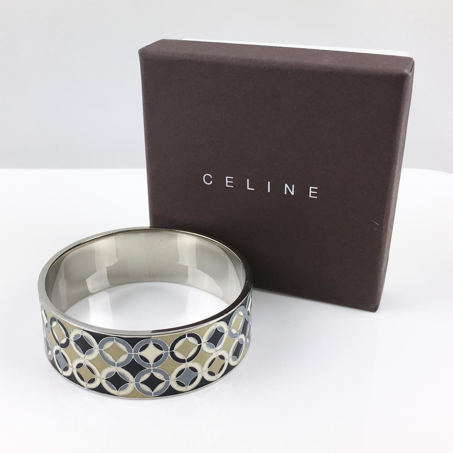 This lovely Celine Paris silver plate bangle bracelet boasts a chunky sliced band shape with a geometric modernist enameled design in assorted black, gray, beige, and ivory colors. The piece is marked 