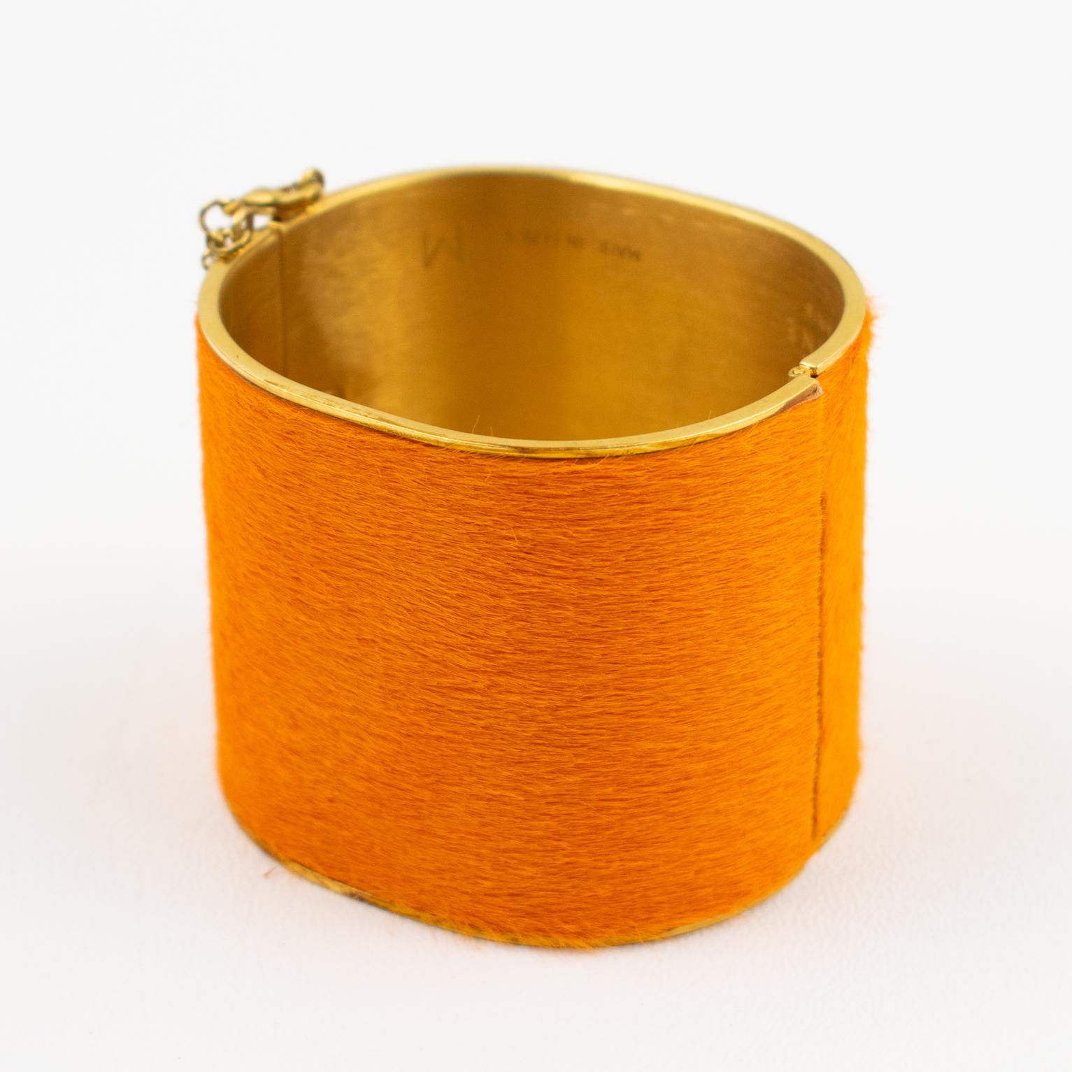 This refined Celine Paris gilt metal clamper bracelet is from the Phoebe Philo Collection. The bangle features an oversized manchette edge cuff shape with orange pony calfskin. The hinge push clasp closure has a security chain. The bracelet is