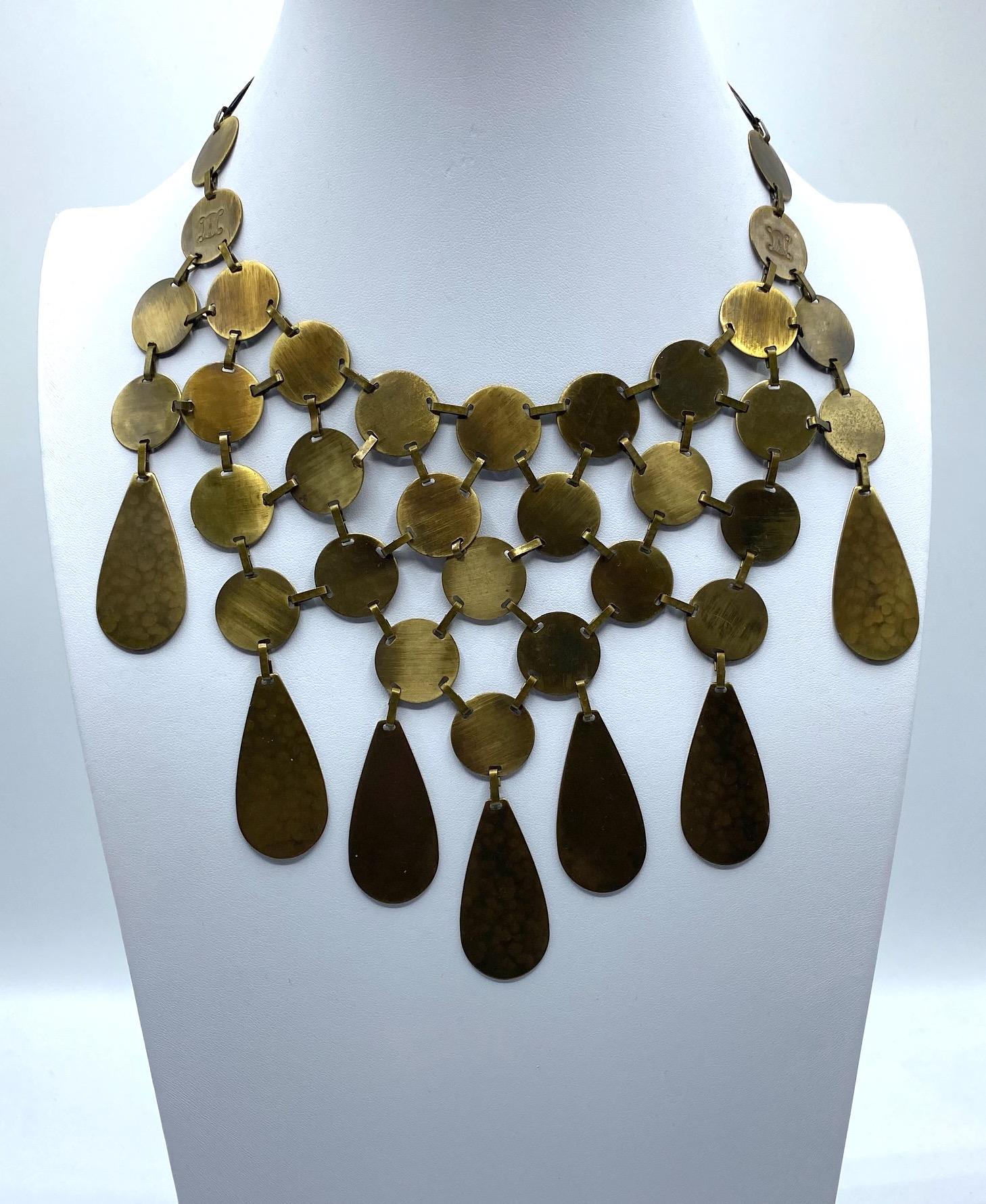 Presented is an amazing Celine bib style necklace in patinated antique bronze finish. It is comprised of .75 of an inch lightly martele' textured antique bronze finished disks with flat band connector links. Along the bottom row are seven pear shape