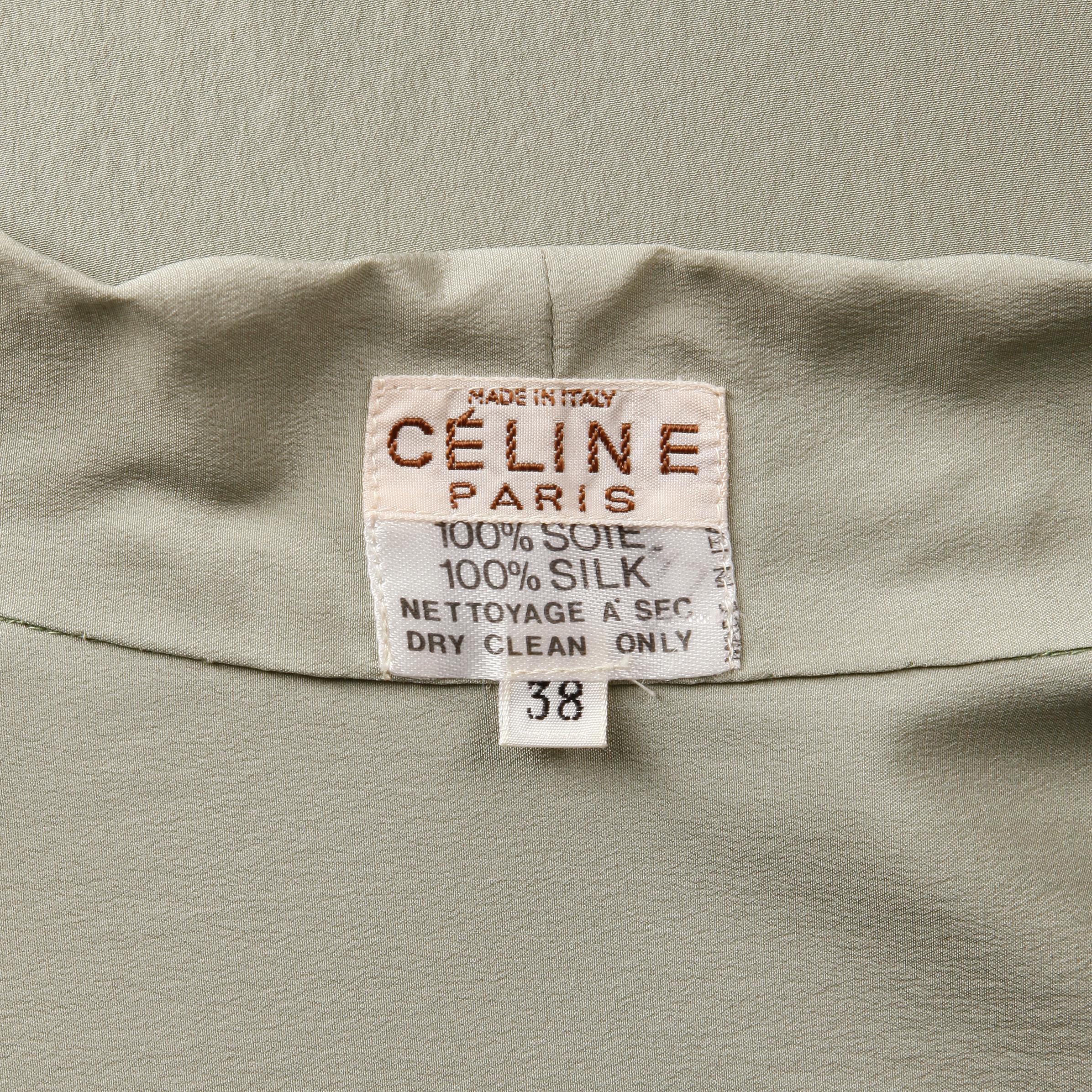 Gorgeous vintage 1970s sage green silk blouse with an ascot tie by Celine Paris. Decorative hand done embroidery featuring the Celine logo on the front of the blouse. Unlined with front button and tie closure. 100% silk. The marked size is 38, and