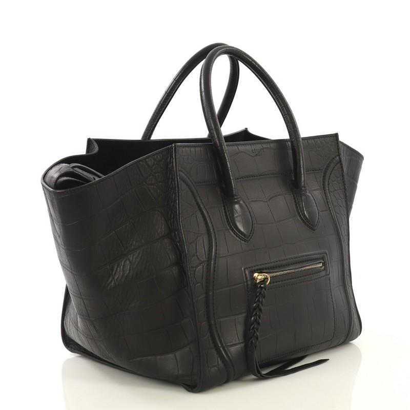 This Celine Phantom Bag Crocodile Embossed Leather Medium, crafted from black crocodile embossed leather, features dual rolled handles, exterior front zip pocket, and aged gold-tone hardware. It opens to a black suede interior with zip pocket.