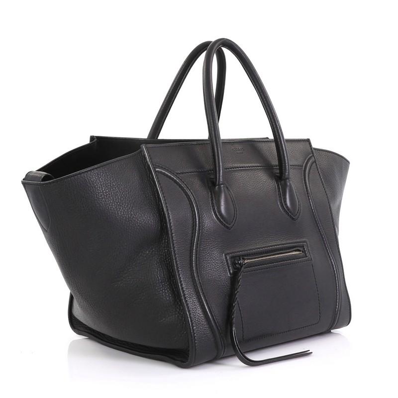 Diese Celine Phantom Bag Grainy Leather Medium ist aus schwarzem Leder gefertigt und verfügt über zwei gerollte Ledergriffe, ein Reißverschlussfach auf der Vorderseite und goldfarbene Beschläge. Das Innere der Tasche ist aus schwarzem Wildleder und
