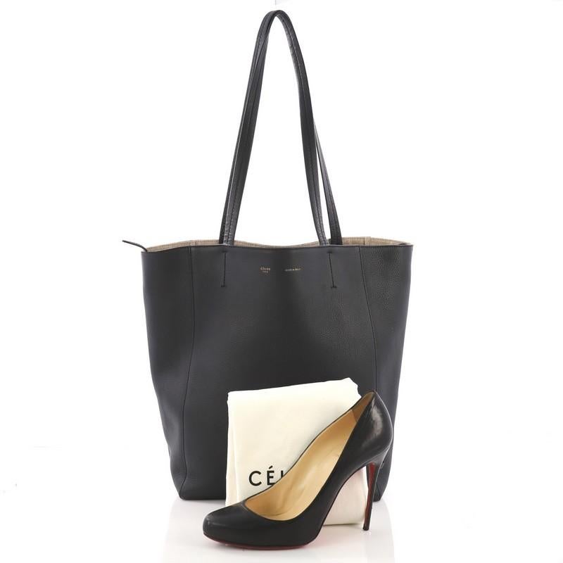 This Celine Phantom Cabas Tote Leather Small, crafted in black leather, features dual slim leather handles, stamped Celine logo, and gold-tone hardware. It opens to a beige canvas interior with side zip and slip pockets. **Note: Shoe photographed is